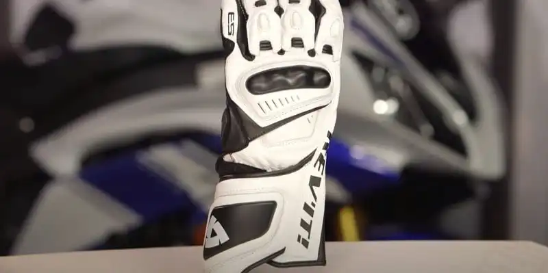 The image shows a close-up view of the REV'IT! Jerez 3 motorcycle glove. The glove is white with black and gray accents. It has protective padding and armor on the knuckles and fingers. The glove is made of leather or a similar durable material suitable for motorcycle riding.